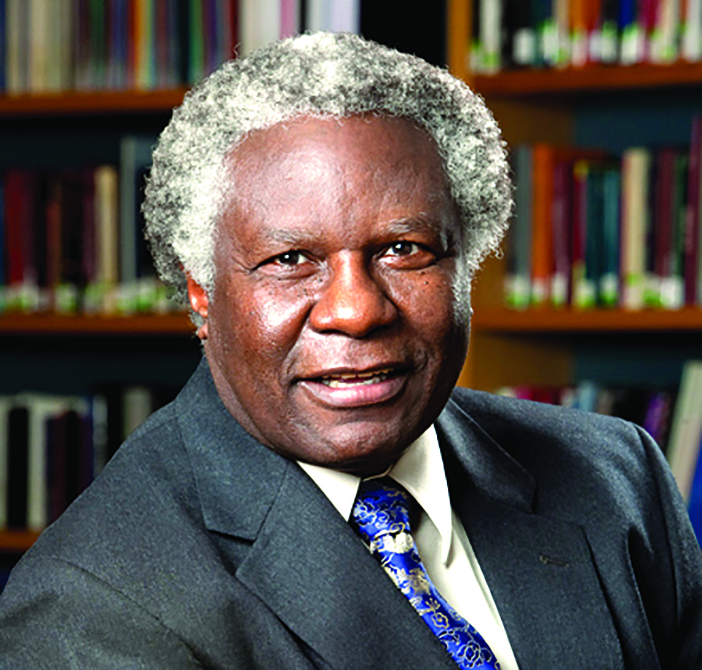 Calestous Juma sits in front of a bookshelf